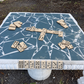 Square concrete domino table with dominoes on its blue mosaic tile top