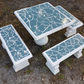 Square concrete domino table and bench set with blue mosaic tile, set up outdoors