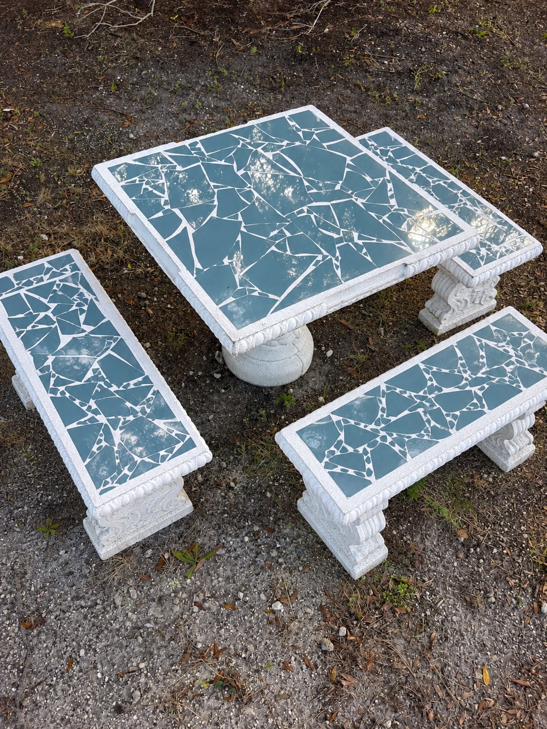 Square concrete domino table and bench set with blue mosaic tile, set up outdoors