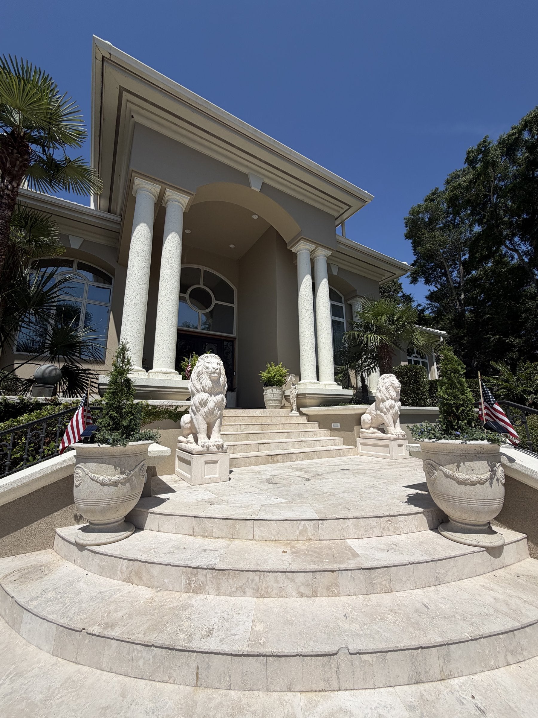 Pair of concrete lion statues flanking a grand estate entrance staircase