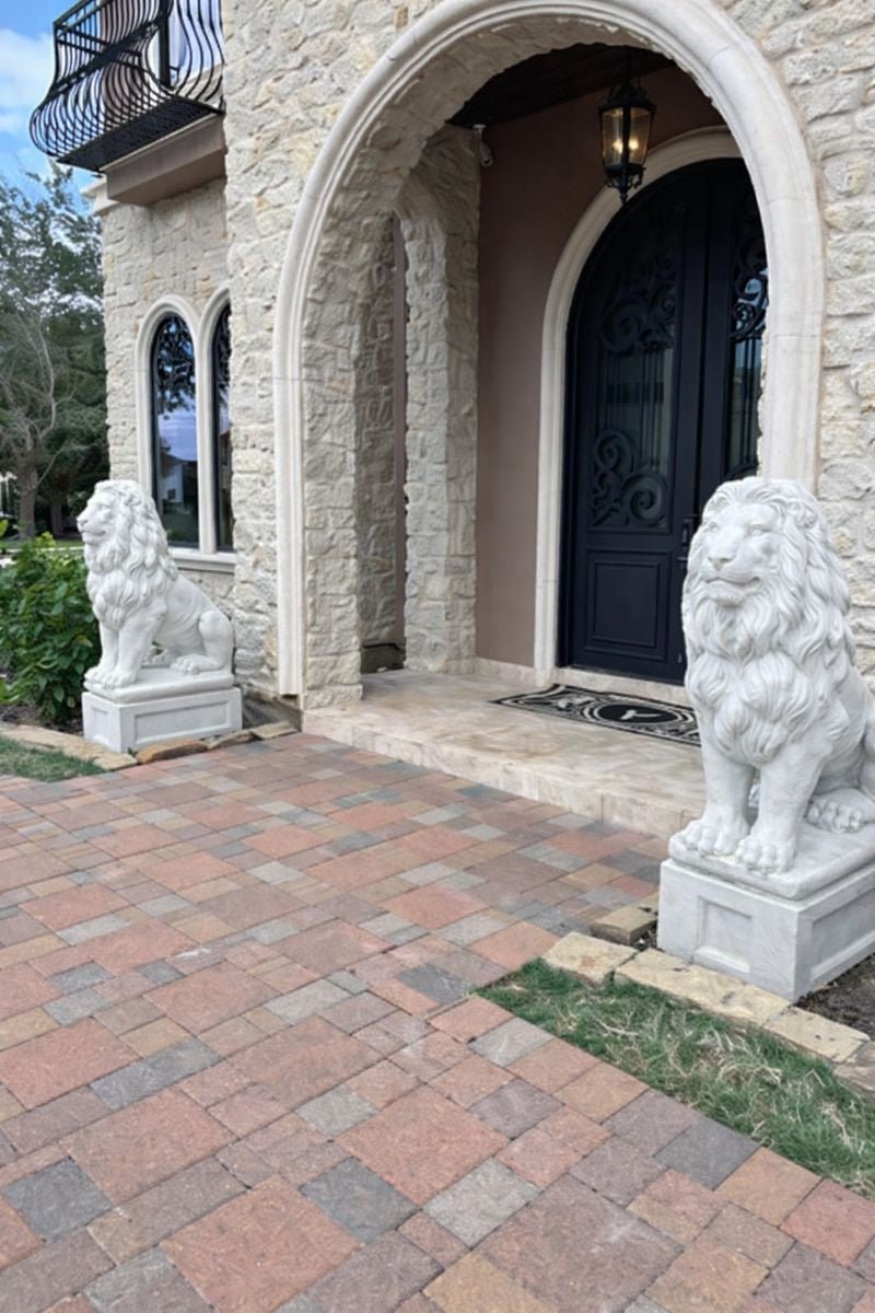 Large Florida Home receives concrete lion statue on square pedestal at entrance of stone estate