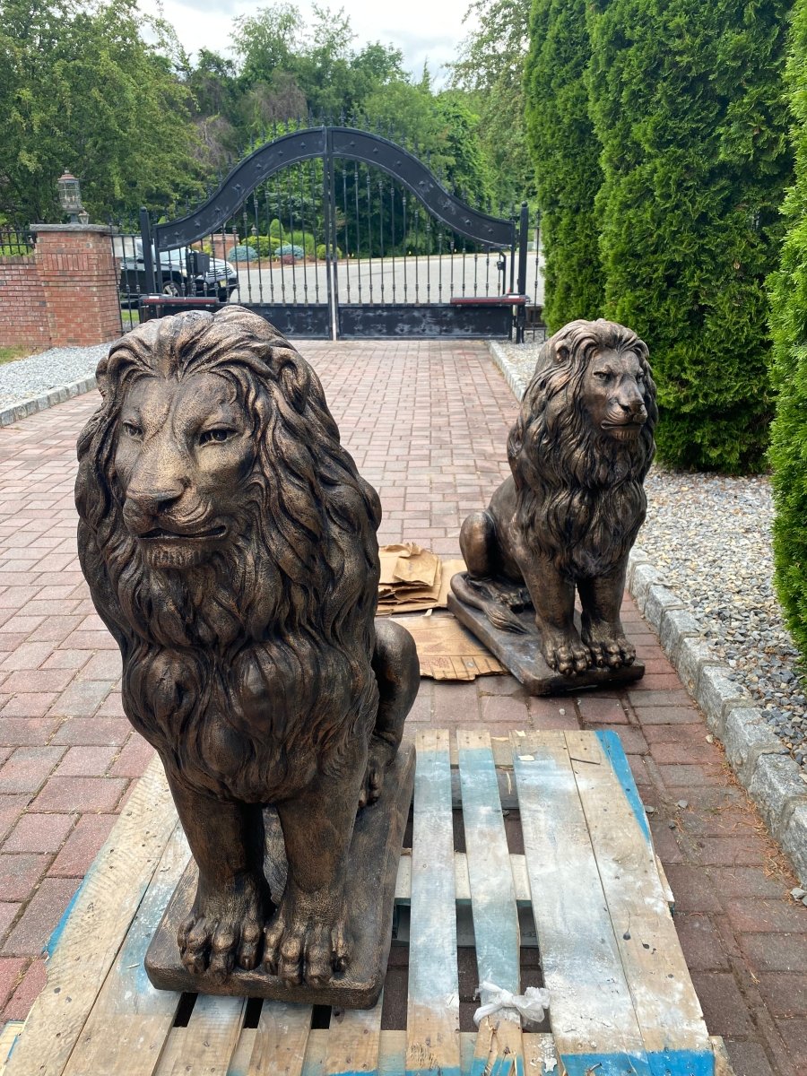 Pair of bronze concrete lion statues on wooden pallets recently delivered