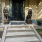 Large concrete lion statues flanking outdoor steps leading to a porch entrance