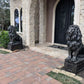 Black and silver concrete lion statues on rectangular pedestal at entrance of house