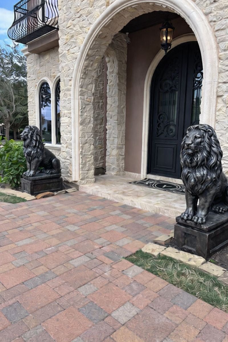 Black and silver concrete lion statues on rectangular pedestal at entrance of house